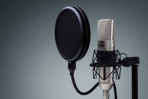 Studio microphone and pop shield on mic stand against gray backg